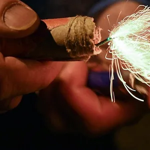 Eine Hand hält einen Feuerwerkskörper, der Funken sprüht.
