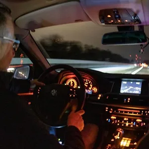 Zwei Polizisten sitzen in einem Auto, man sieht das Cockpit und durch die Frontscheibe eine Autobahn.