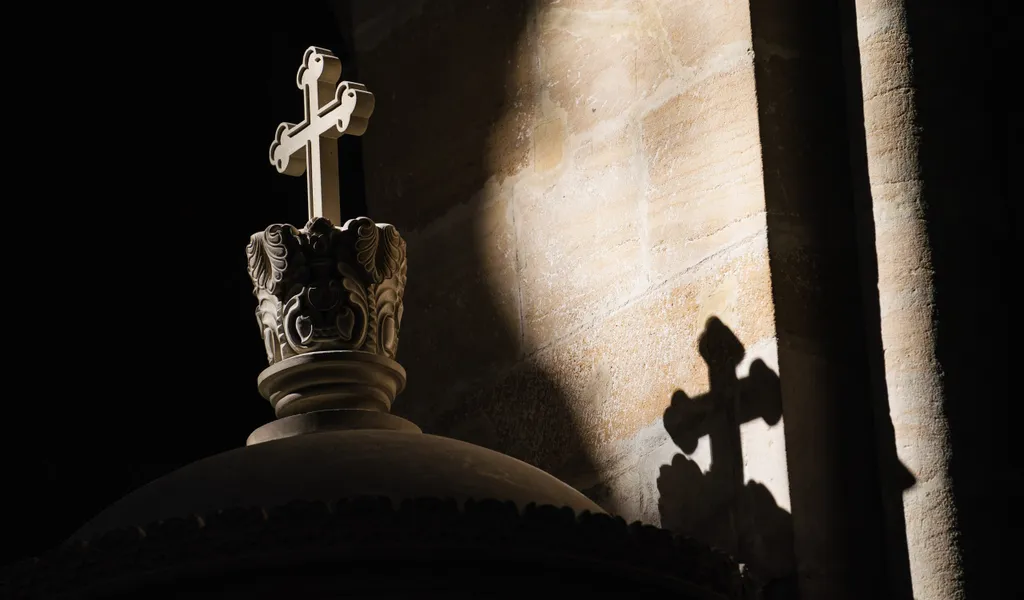 Ein Lichtstrahl fällt im Bamberger Dom auf ein Kreuz.