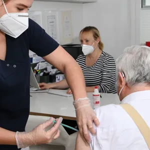 Eine Ärztin impft einen Patienten