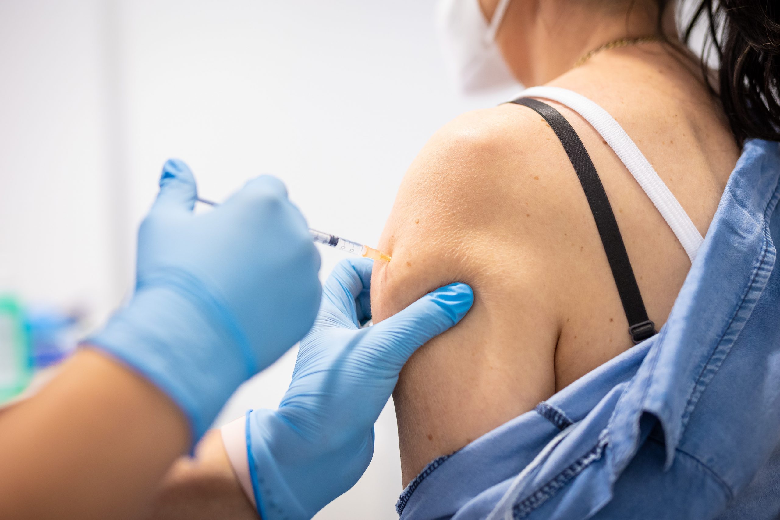 Frau bekommt eine Coronaimpfung in den Oberarm gespritzt.