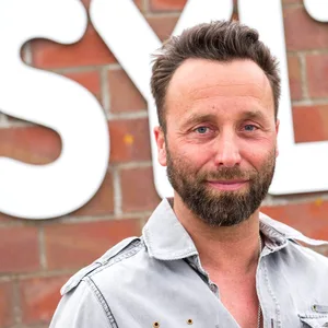 Dirk Lins steht vor einem Sylt-Schriftzug