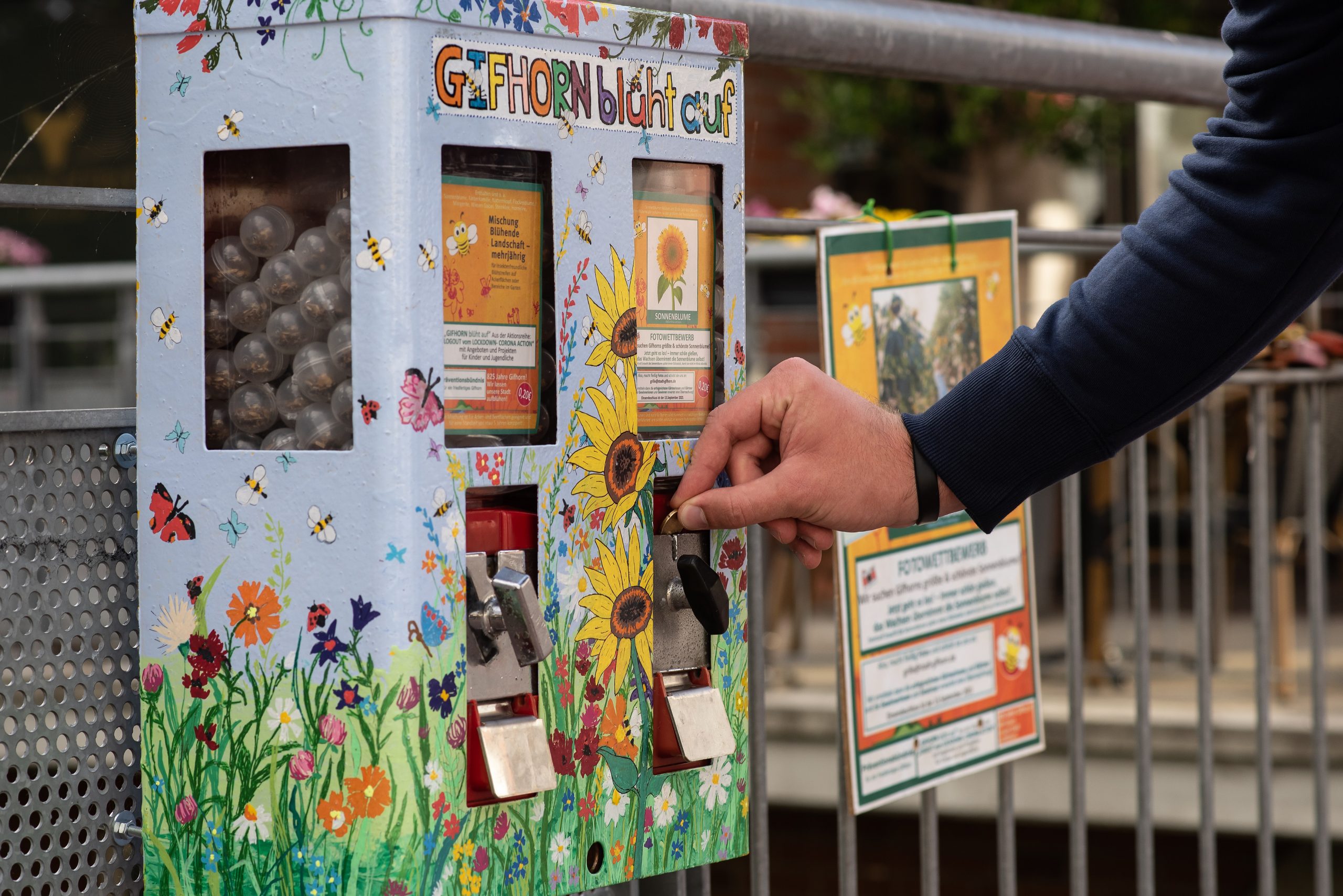 Ein Mann wirft 20 Cent in einen Kaugummiautomaten mit Blumensamen