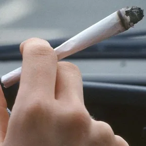 Jemand hält am Steuer eines Autos einen Joint.