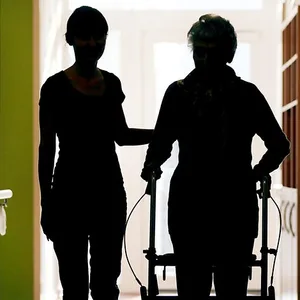 Eine Pflegerin und eine ältere Frau mit Rollator