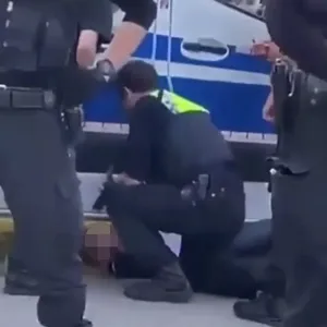 Ein Polizist fixiert den Jugendlichen am Boden.
