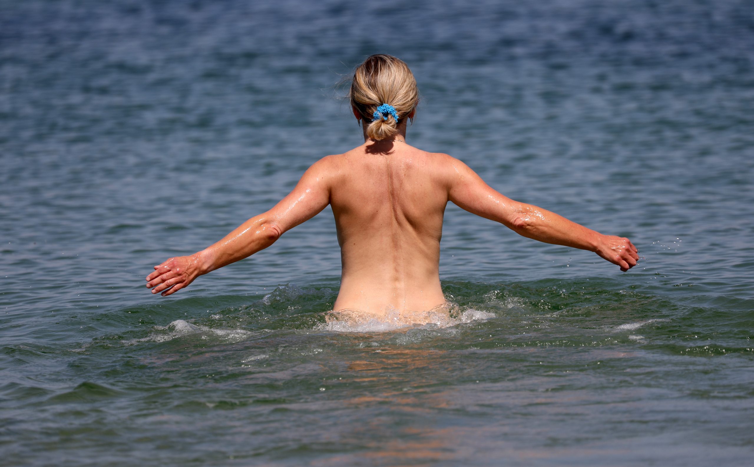 Warnemünde: Eine Frau geht an einem FKK-Abschnitt des Ostseebades ins Wasser.