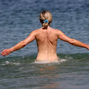 Warnemünde: Eine Frau geht an einem FKK-Abschnitt des Ostseebades ins Wasser.
