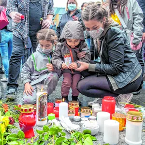 Menschen legen Kerzen und Blumen für fünf ermordete Kinder nieder