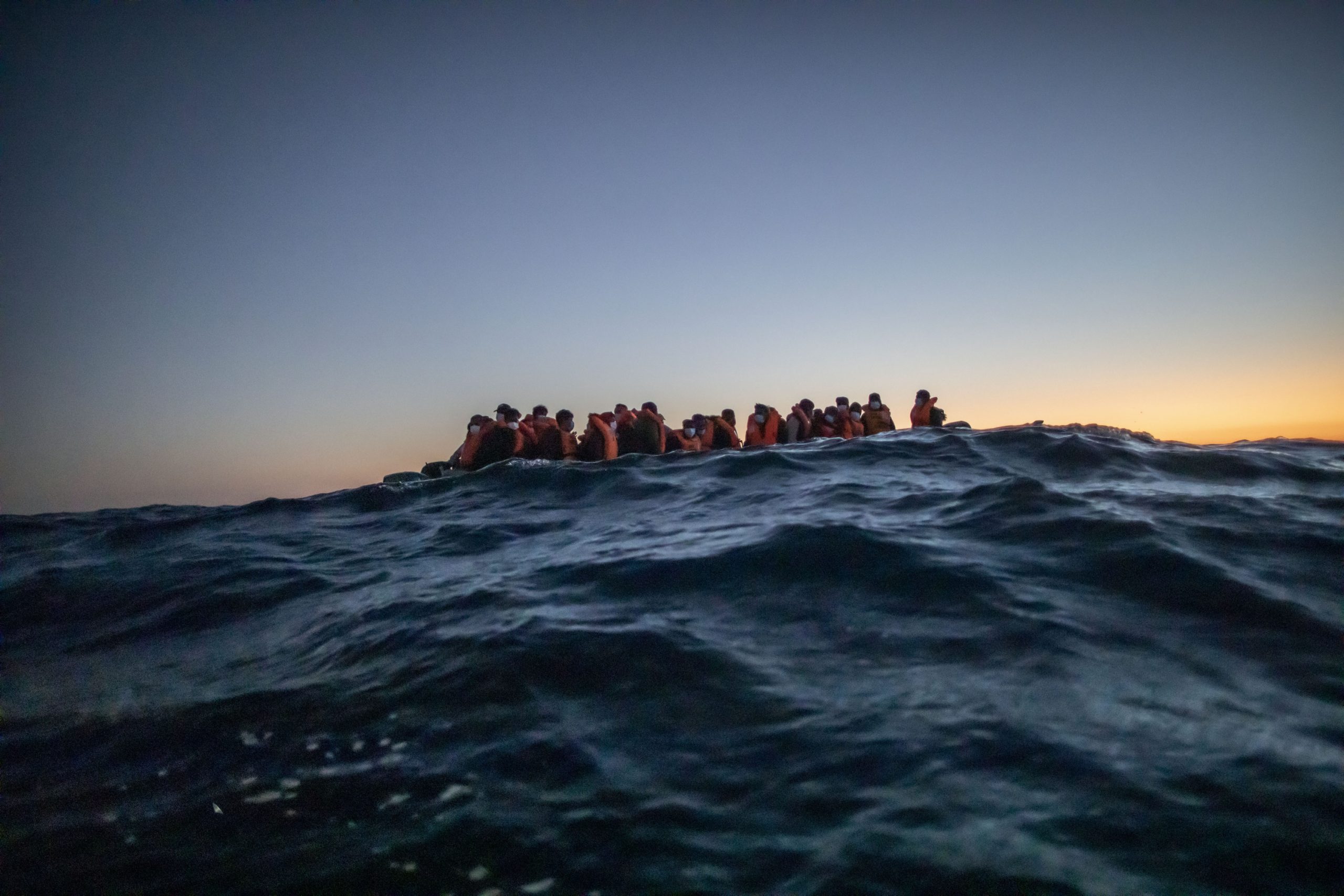 Migranten aus verschiedenen afrikanischen Nationen warten in einem Boot auf Helfer