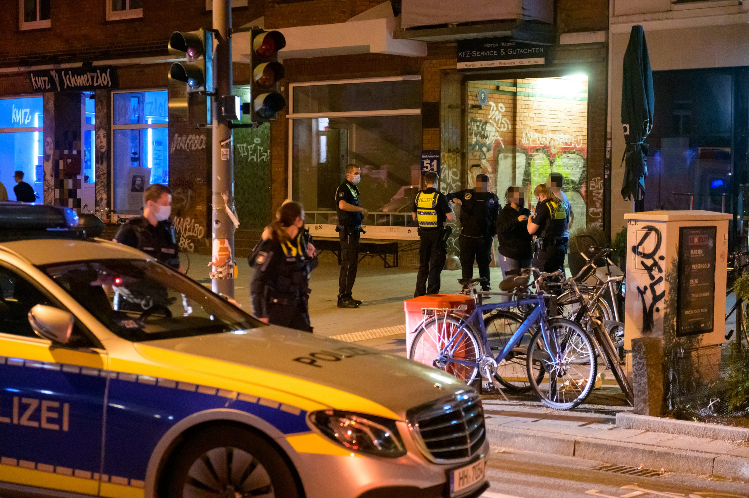 Polizisten befragen am Tatort an der Weidenallee Zeugen.