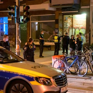 Polizisten befragen am Tatort an der Weidenallee Zeugen.