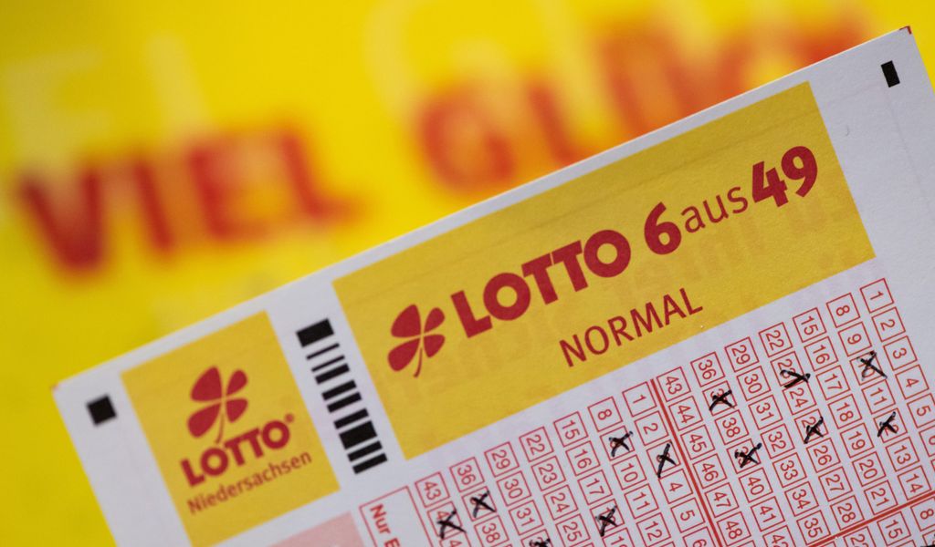 Ein Lottoschein mit der Aufschrift „Lotto 6 aus 49“ ist vor einem Schriftzug „Viel Glück“ zu sehen.