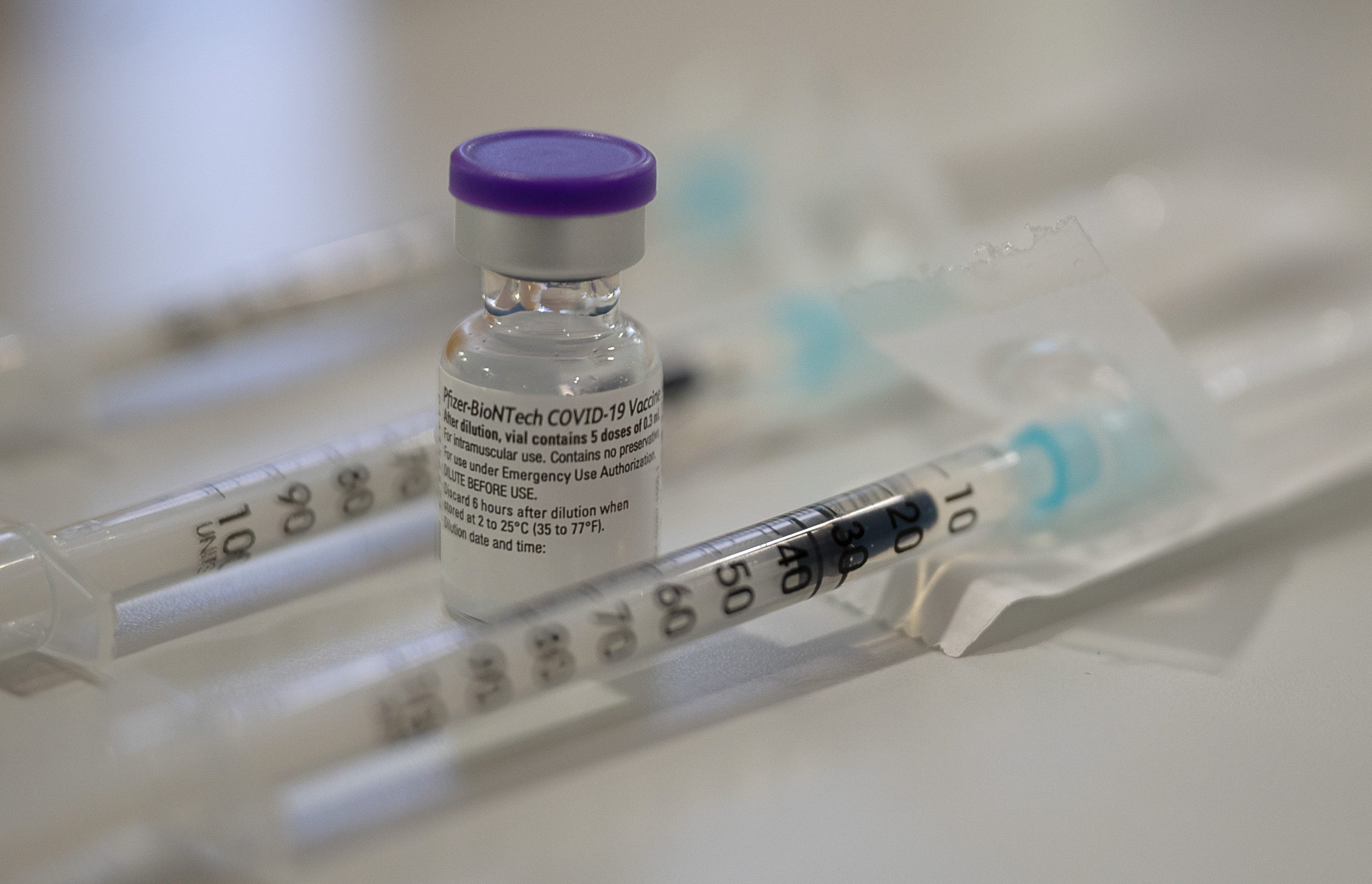 Eine Ampulle mit dem Corona-Impfstoff von Biontech/Pfizer steht zwischen bereits aufgezogenen Spritzen