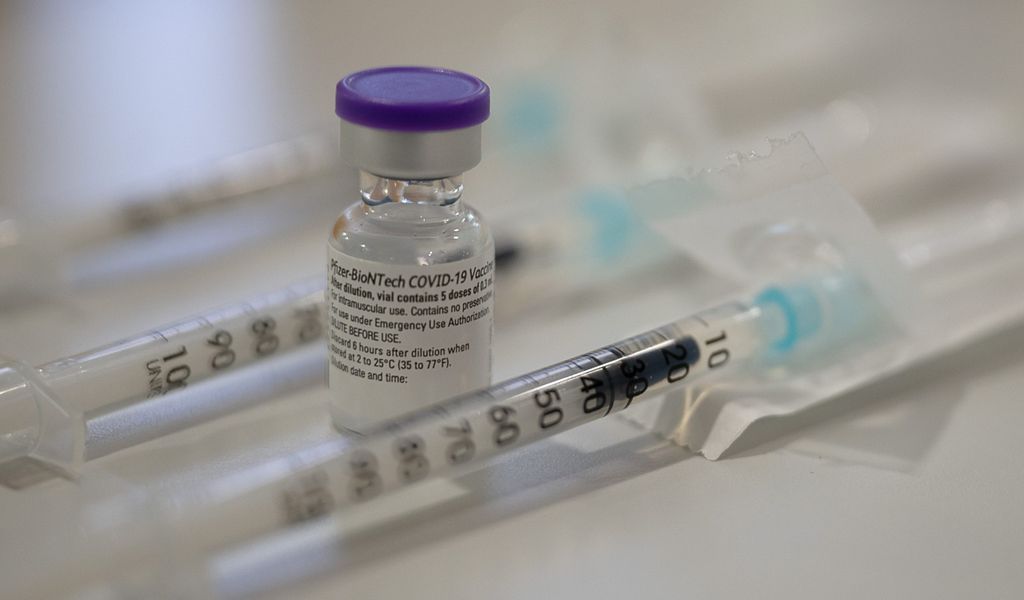 Eine Ampulle mit dem Corona-Impfstoff von Biontech/Pfizer steht zwischen bereits aufgezogenen Spritzen