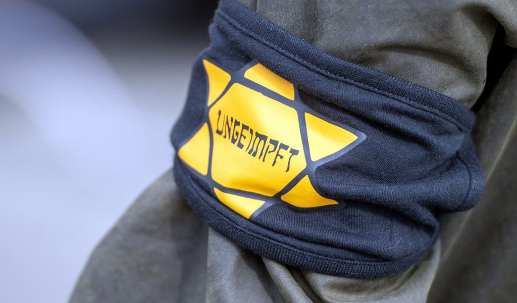 Bei einer Demonstration gegen die Einschränkungen durch die Pandemie-Maßnahmen der Bundesregierung am Brandenburger Tor trägt ein Teilnehmer eine Armbinde mit einem gelben Stern, der an einen Judenstern erinnern soll, mit der Aufschrift „Ungeimpft“.