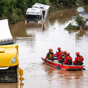 Helfer der Wasserwacht untersuchen von einem Boot aus Lastwagen, die auf der überfluteten Bundesstraße 265 stehen.