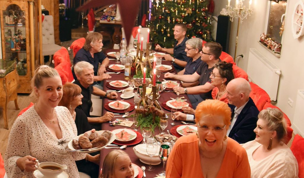Dietmar und Martina Sawatzke sitzen mit Familie und Freunden unter Weihnachtssternen am festlich gedeckten Tisch