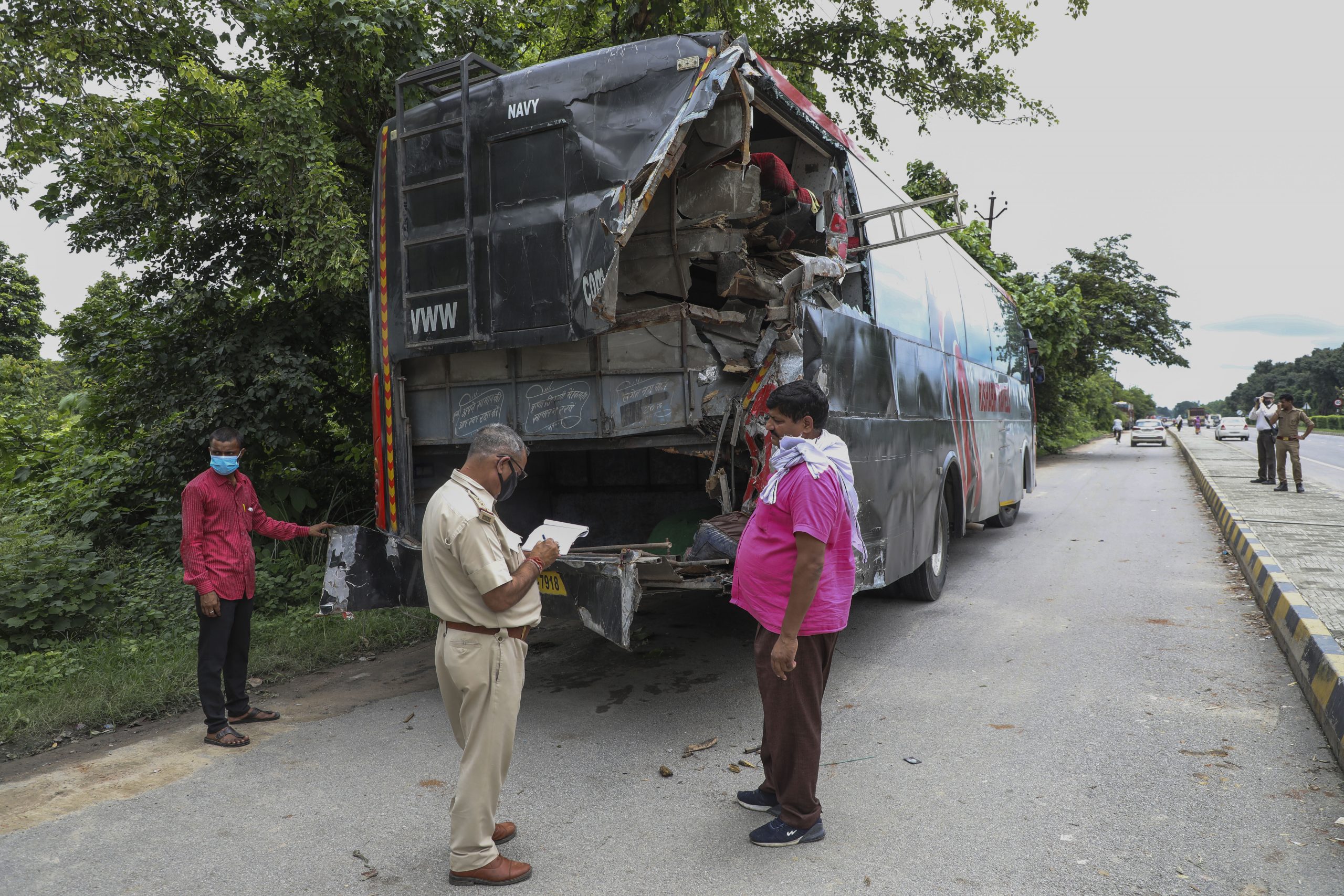 Ein Polizist macht Notizen an der Unfallstelle vor dem beschädigten Bus in Indien.