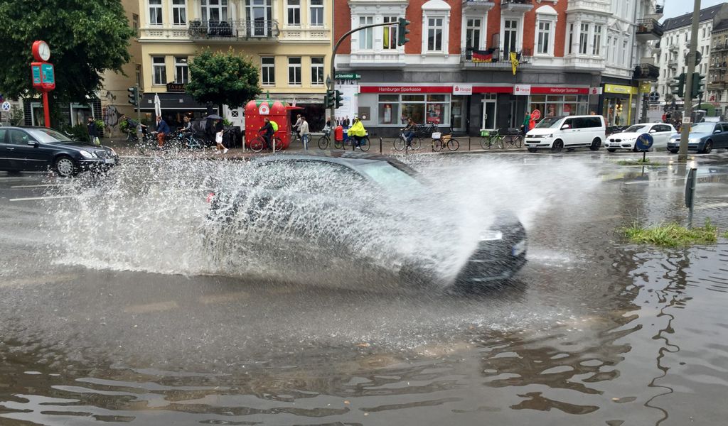 Auto fährt auf überfluteter Straße