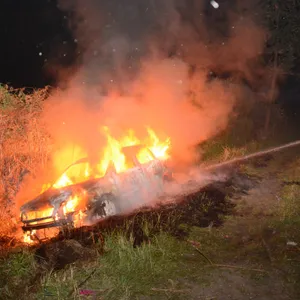 Ein Feuerwehrmann löscht das in Brand geratene Auto.