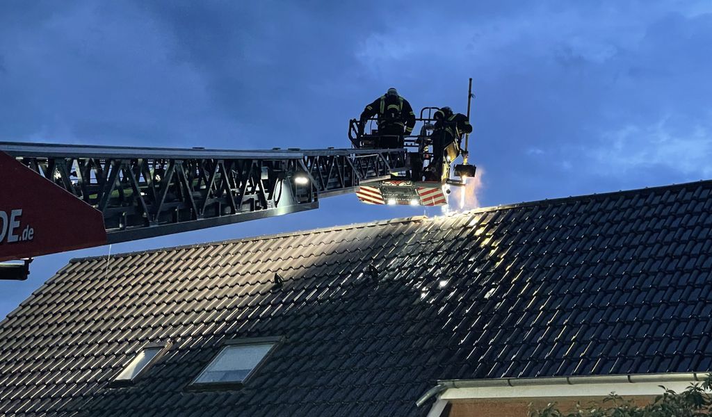Feuerwehrleute löschen auf einer Drehleiter einen Dachbrand