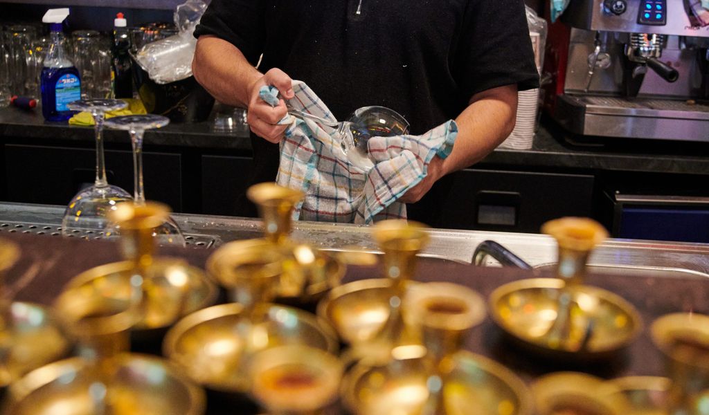 Ein Mitarbeiter Restaurants poliert die Weingläser.
