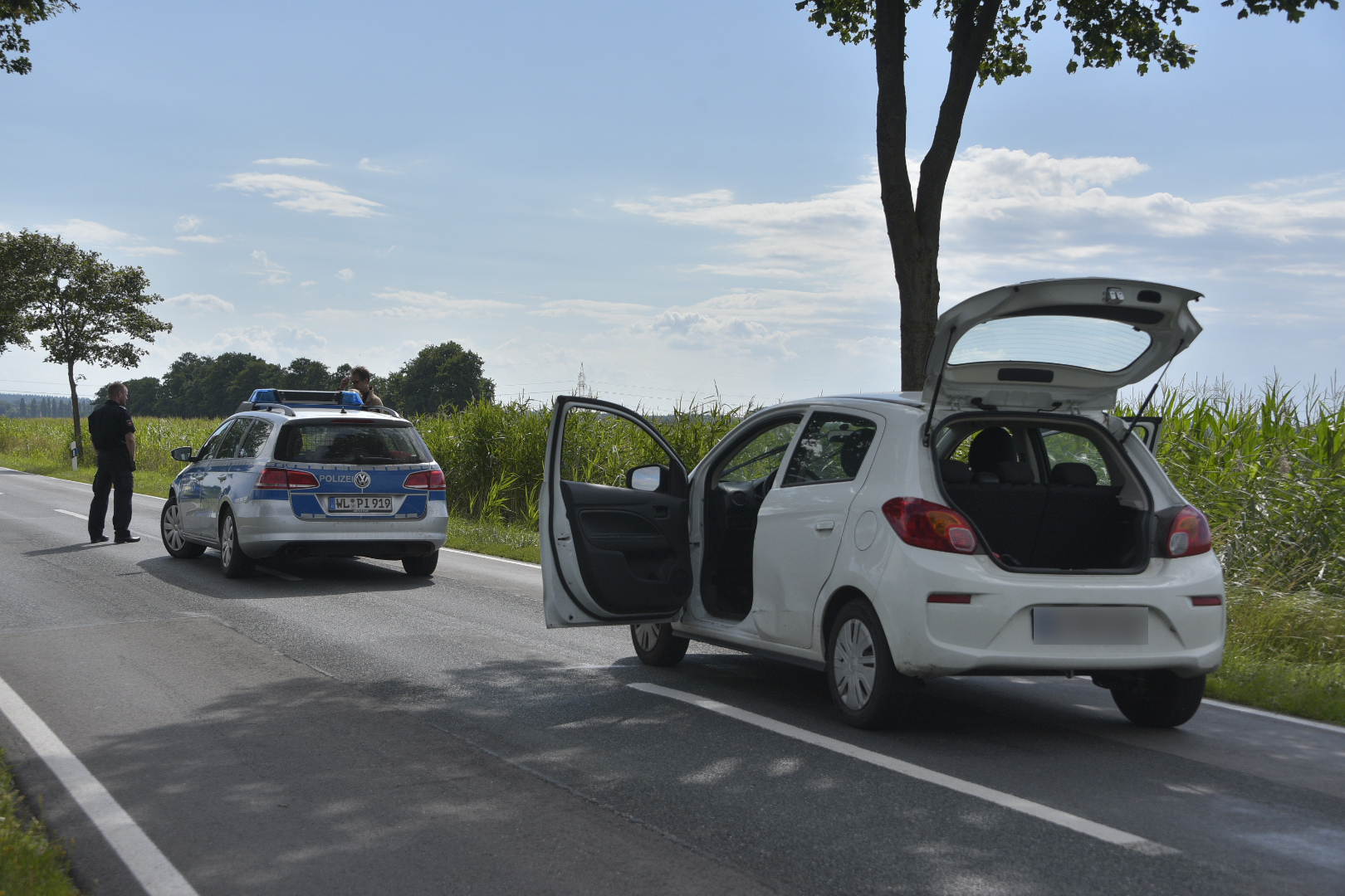 Ein Polizeiauto und ein weißer Opel Corsa auf einer Landstraße im Kreis Harburg