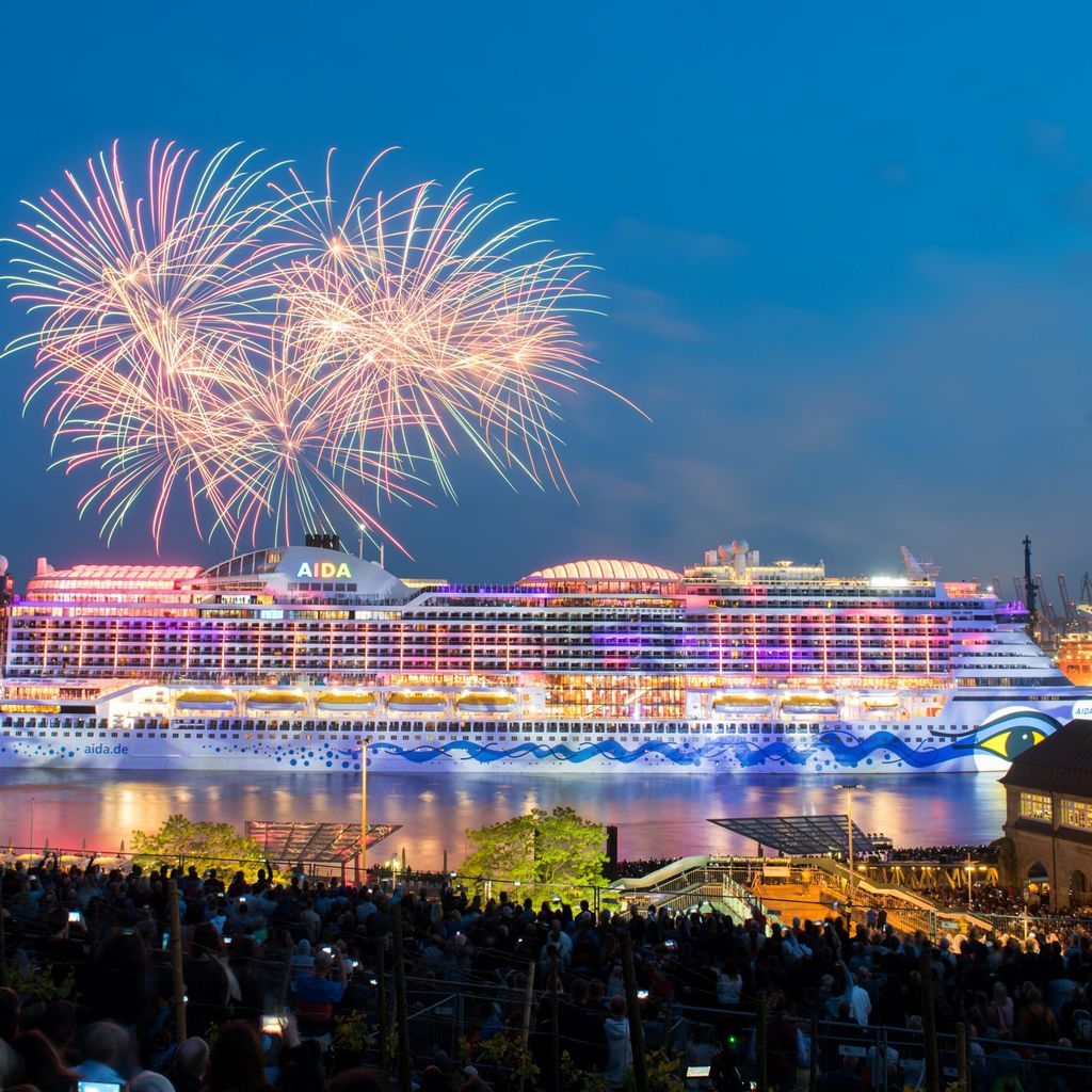 Zahlreiche Menschen verfolgen an den Landungsbrücken während des Hamburger Hafengeburtags ein Feuerwerk über dem Kreuzfahrtschiff „Aida Perla“.