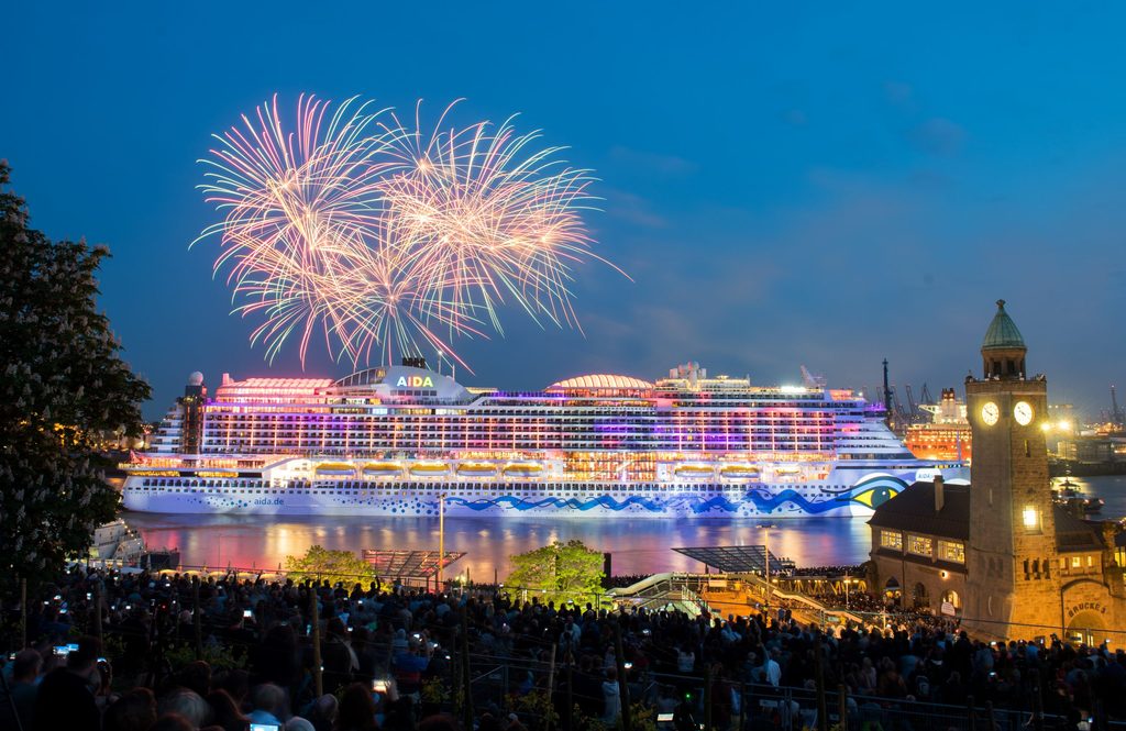 Zahlreiche Menschen verfolgen an den Landungsbrücken während des Hamburger Hafengeburtags ein Feuerwerk über dem Kreuzfahrtschiff „Aida Perla“.