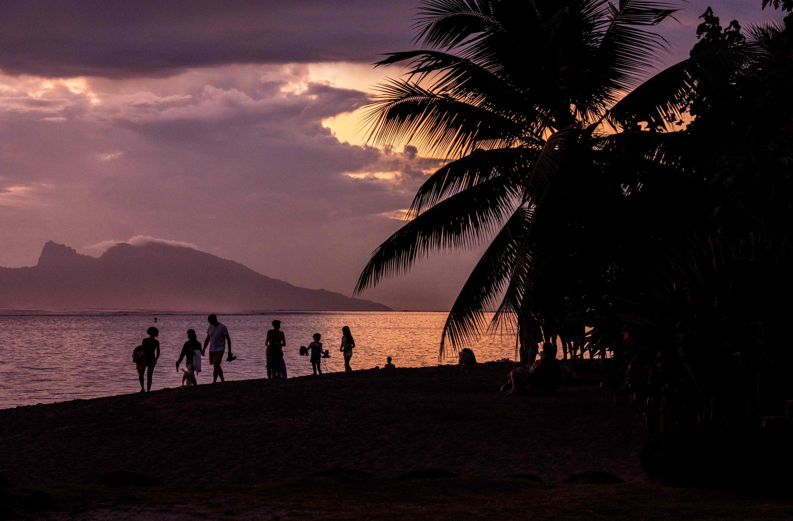 Menschen genießen den Sonnenuntergang am Strand von Punaauia, Vororte von Papeete, Westküste von Tahiti, Französisch-Polynesien.
