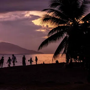 Menschen genießen den Sonnenuntergang am Strand von Punaauia, Vororte von Papeete, Westküste von Tahiti, Französisch-Polynesien.