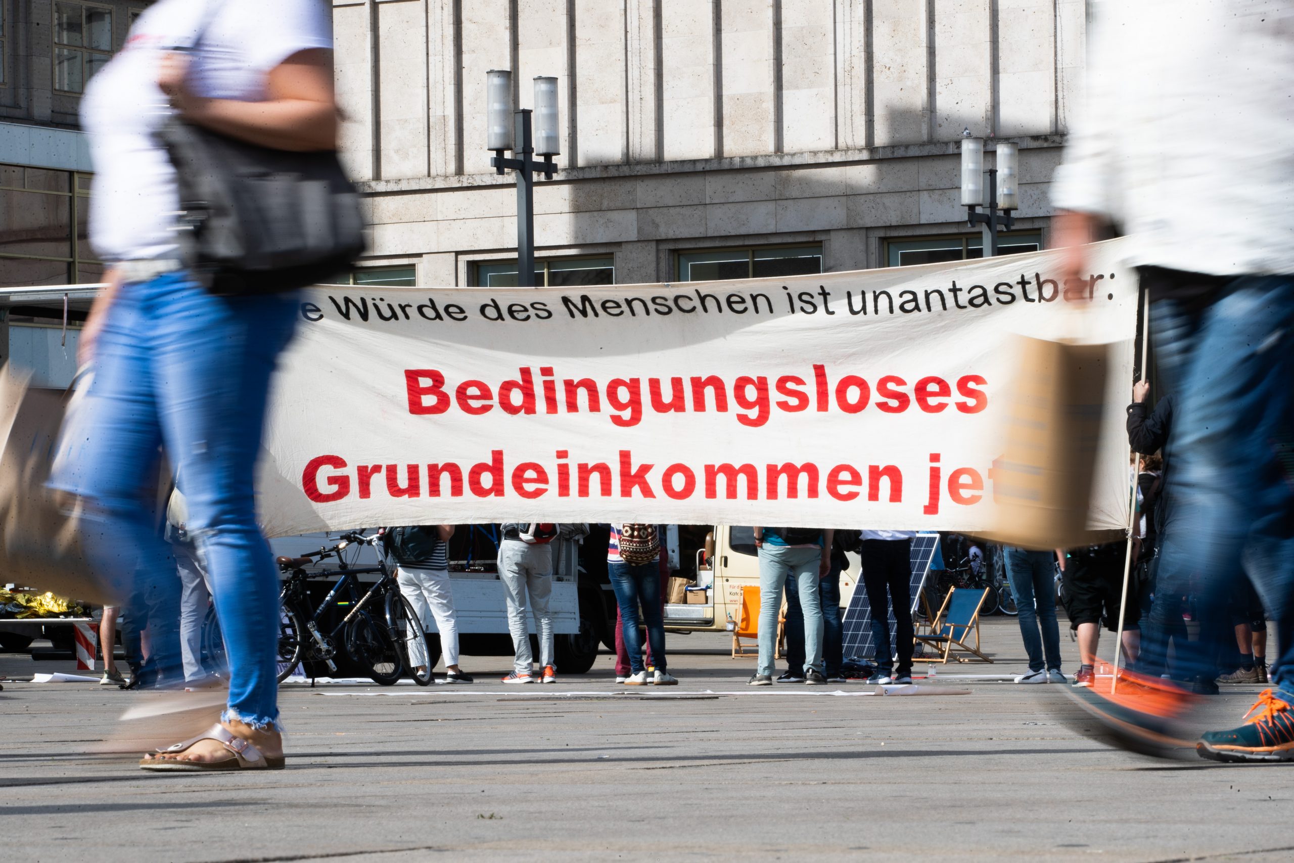 „Bedingungsloses Grundeinkommen jetzt!“ steht bei der Auftaktkundgebung einer Demonstration für ein bedingungsloses Grundeinkommen auf dem Alexanderplatz auf einem Banner geschrieben