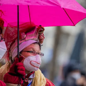 Zwei Karnevalisten unter einem pinken Regenschirm.