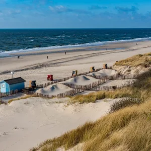 Vereinzelte Strandbesucher laufen an den Dünen am Ufer der Nordsee entlang