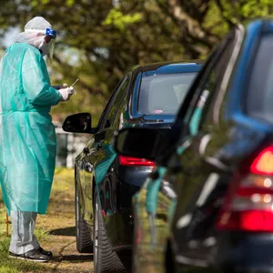 mensch im Schutzanzug an Autos