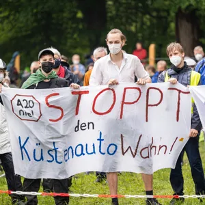 Einige Demonstranten halten bei einer Versammlung gegen den Bau der Autobahn A20 einen Banner mit der Aufschrift „A20 nie! Stoppt den KüstenautoWahn!“.