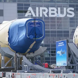Segmente eines Flugzeugrumpfes eines Airbus A350 stehen vor einer Fertigungshalle auf dem Werksgelände des Flugzeugbauers Airbus.
