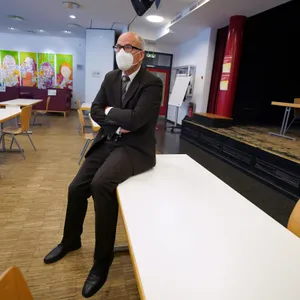 Schulsenator Ties Rabe auf einem Tisch in einem Klassenzimmer