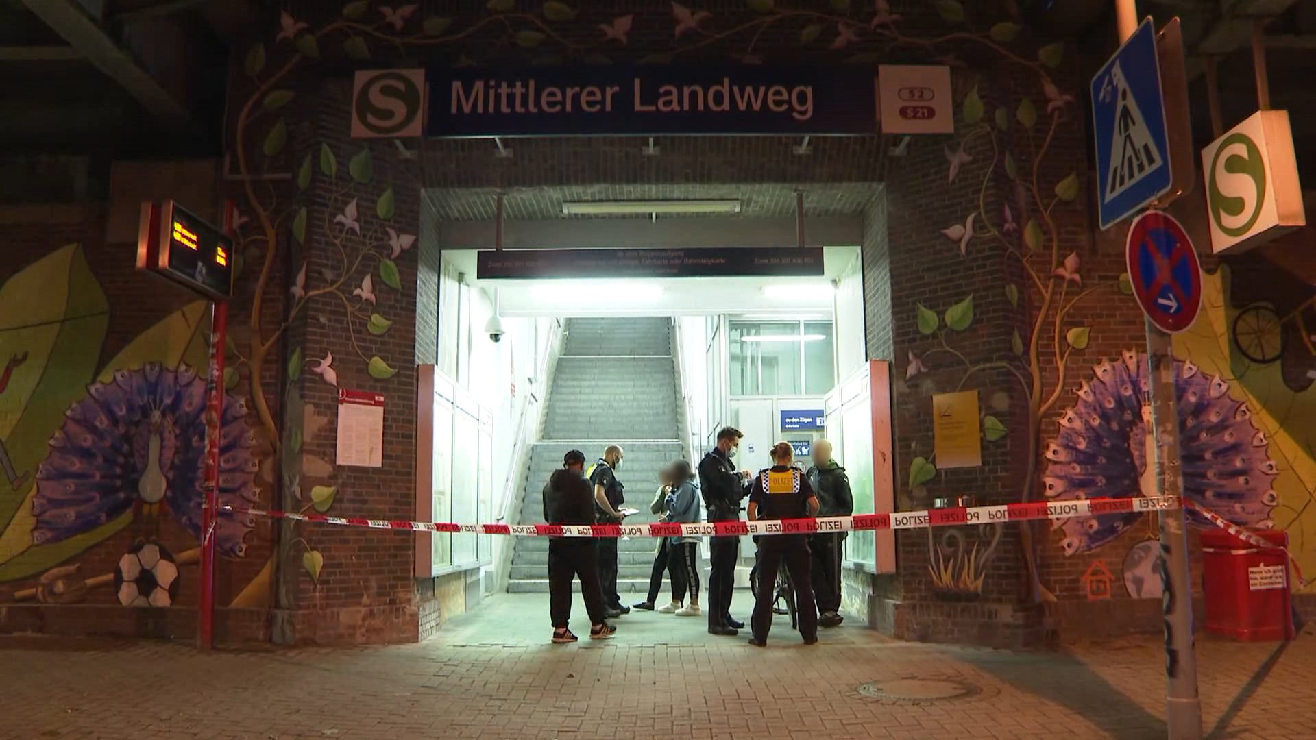 Polizisten befragen Sonntagnacht im Eingangsbereich zum S-Bahnhof Mittlerer Landweg mögliche Zeugen.
