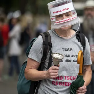 Ein „Querdenken“-Demonstrant läuft mit Plastikeimer auf dem Kopf durch Berlin.