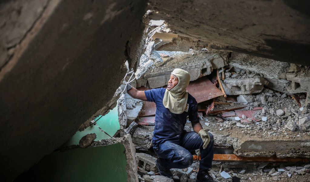 Ein Feuerwehrmann sucht zwischen den Trümmern eines von einem Erdbeben zerstörten Hauses nach Überlebenden.