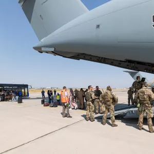 Schutzbedürftige Menschen gehen kurz nach dem Flug aus Kabul zu einem Bus.