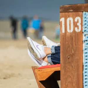 Zwei Personen sitzen am Strand von Dangast in einem Strandkorb. (Symbolbild)