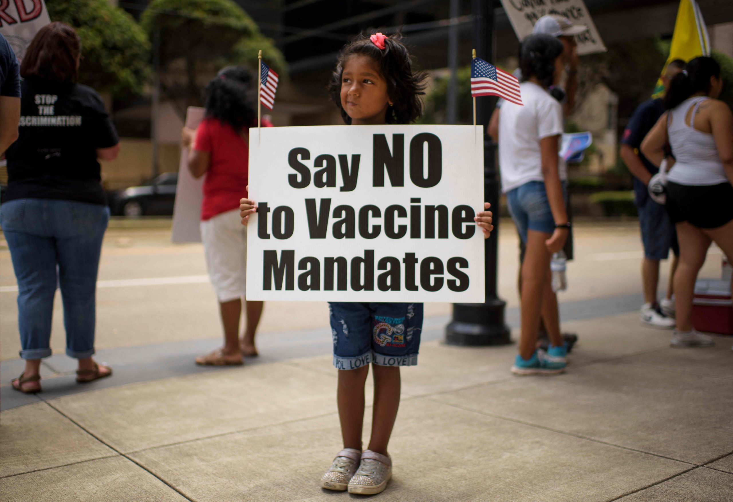 „Sagt nein zur Impfpflicht“, fordert dieses kleine Mädchen in Texas mehr oder weniger freiwillig auf ihrem Plakat.