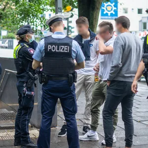 Polizisten und drei Touristen stehen am Bahn-Eingang auf der Reeperbahn