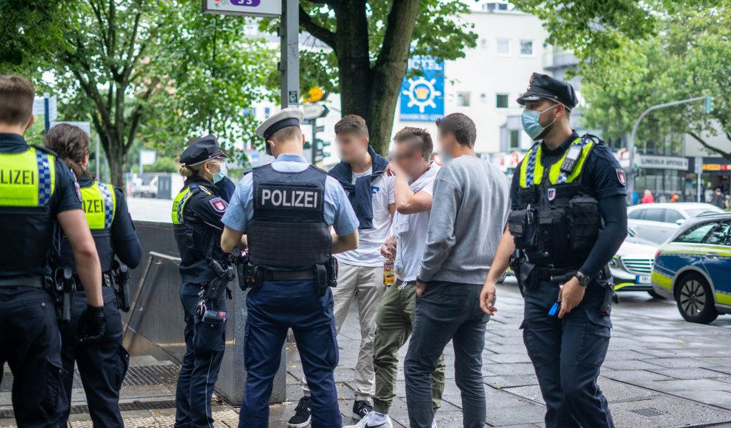 Polizisten und drei Touristen stehen am Bahn-Eingang auf der Reeperbahn