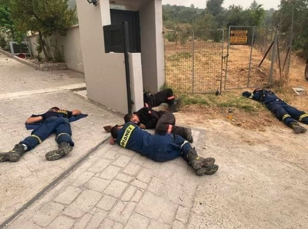Völlig erschöpfte Feuerwehrleute liegen nahe eines Brandherds in Griechenland auf dem Boden.