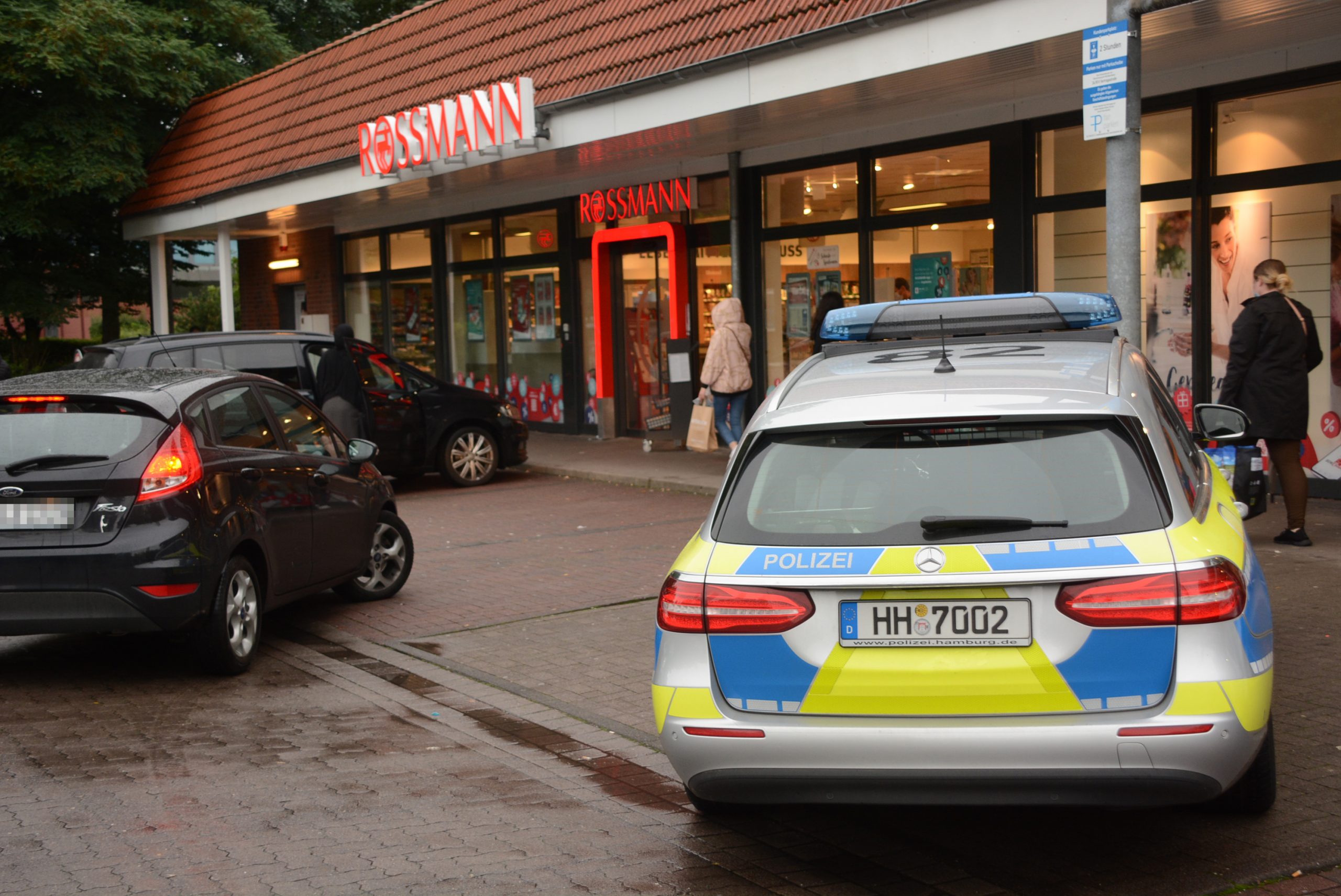 Blick auf eine Rossmann-Filiale, davor ein Polizeiauto