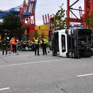 Einsatzkräfte versorgen den Verletzten, der Lkw liegt auf der Seite